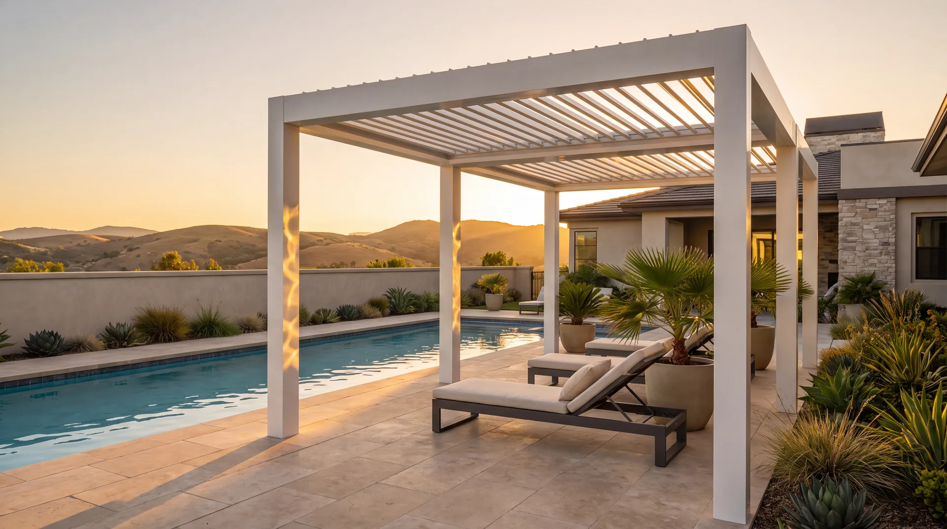 A white freestanding louvered pergola beside a swimming pool at golden hour