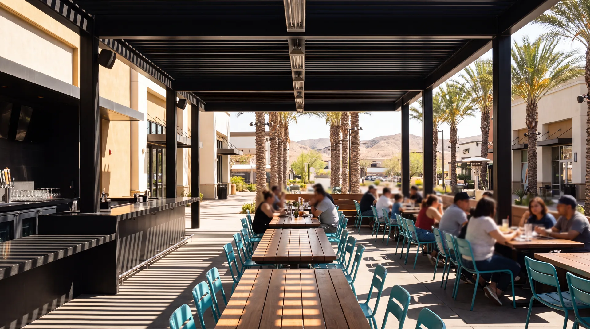 A restaurant dining terrace under a black steel patio cover, sunlight striping the tables