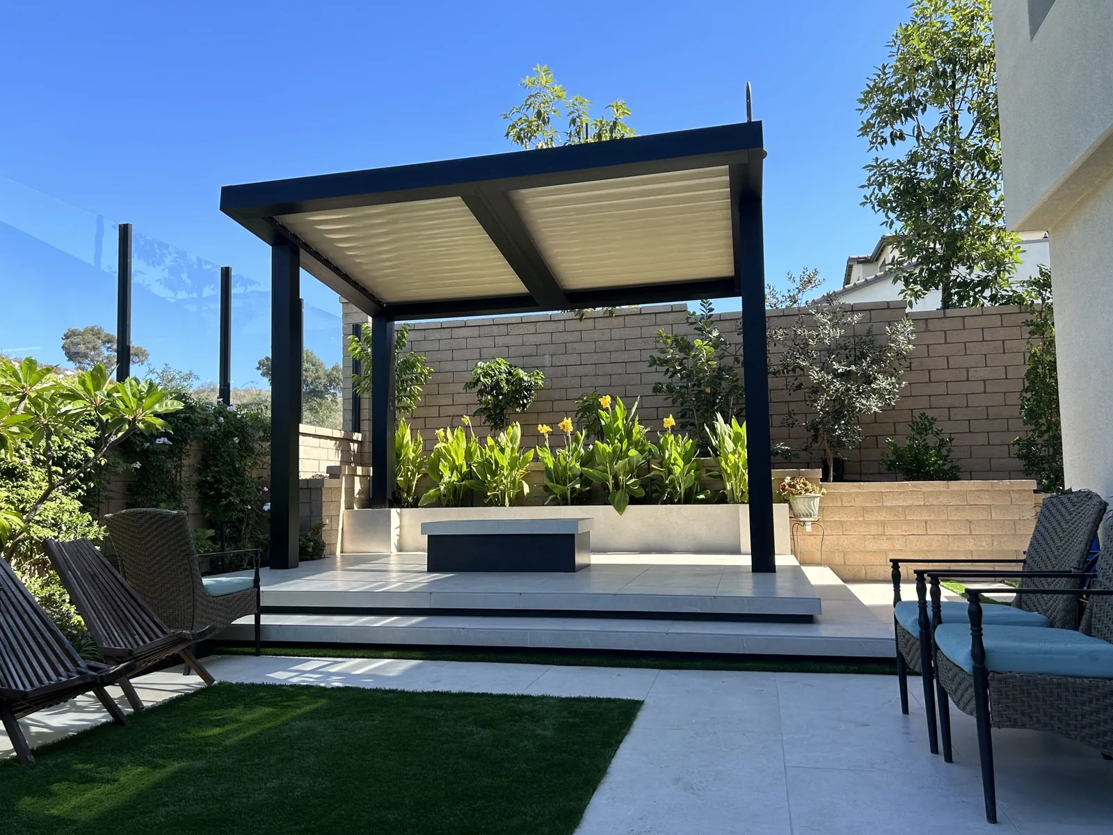 Black freestanding louvered cover over a modern backyard patio
