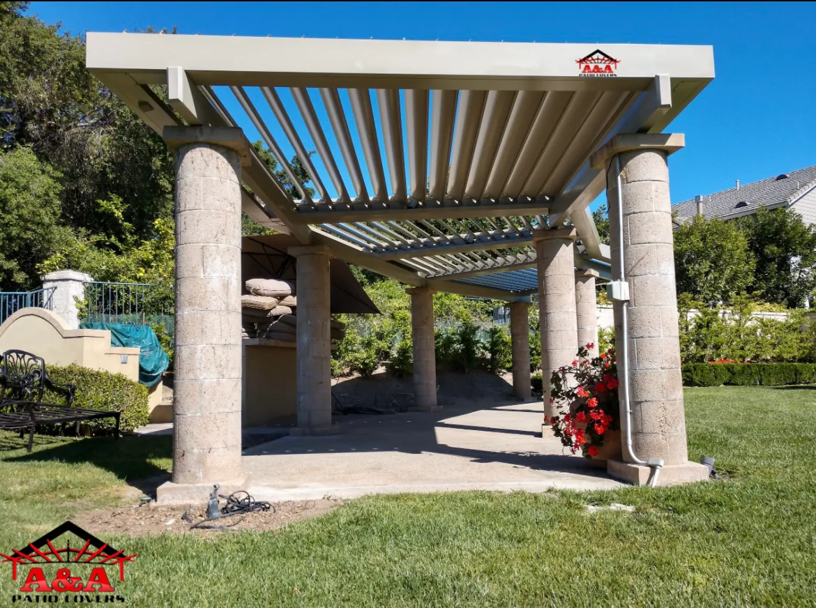 Stone column pergola with louvered roof over a garden seating area