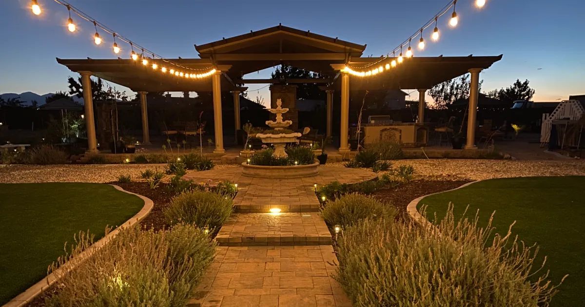 Illuminated pergola and fountain courtyard lit with string lights at night