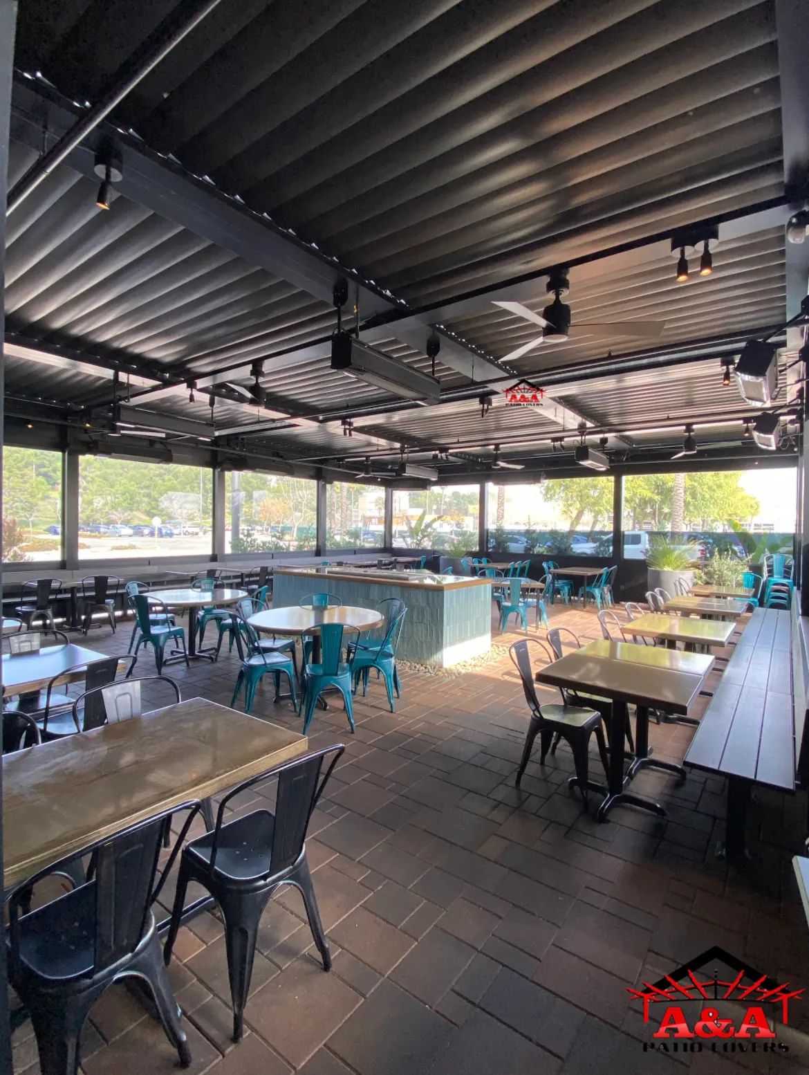 Covered restaurant dining area with exposed steel structure and pendant lighting