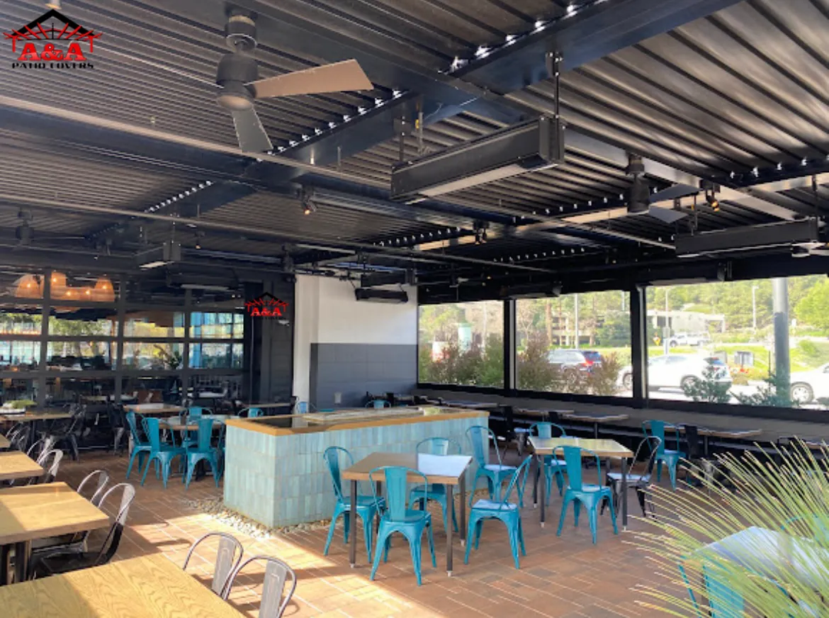 Open-air restaurant terrace under a black steel patio cover with communal seating