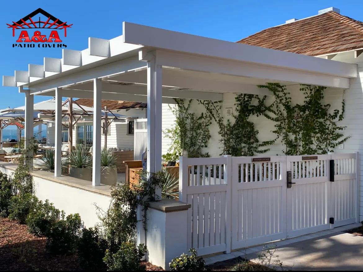 White pergola over a fenced restaurant patio with planters
